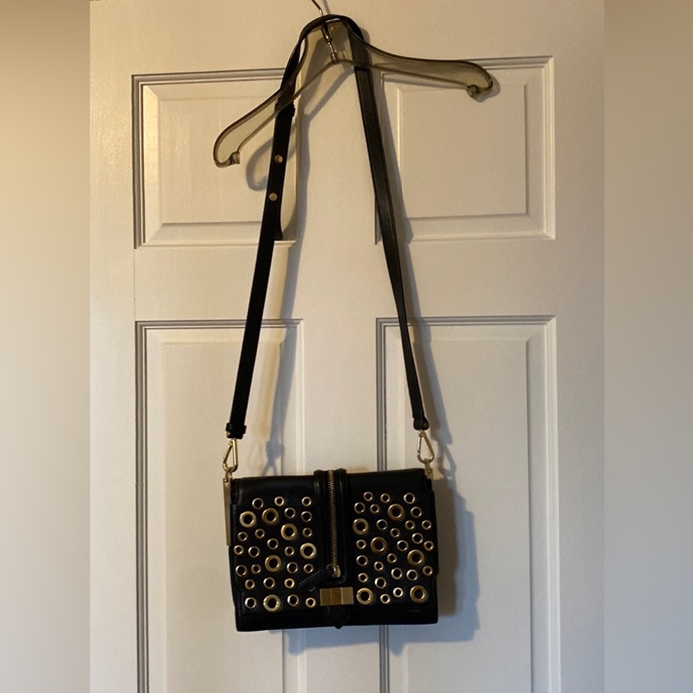 Black purse with gold eyelets and zipper detail.